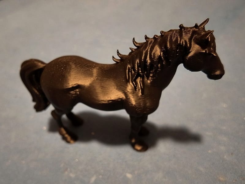 Zwarte 3D-geprinte paardsculptuur in zijaanzicht, met uitgewerkte mane en een vloeiende staart